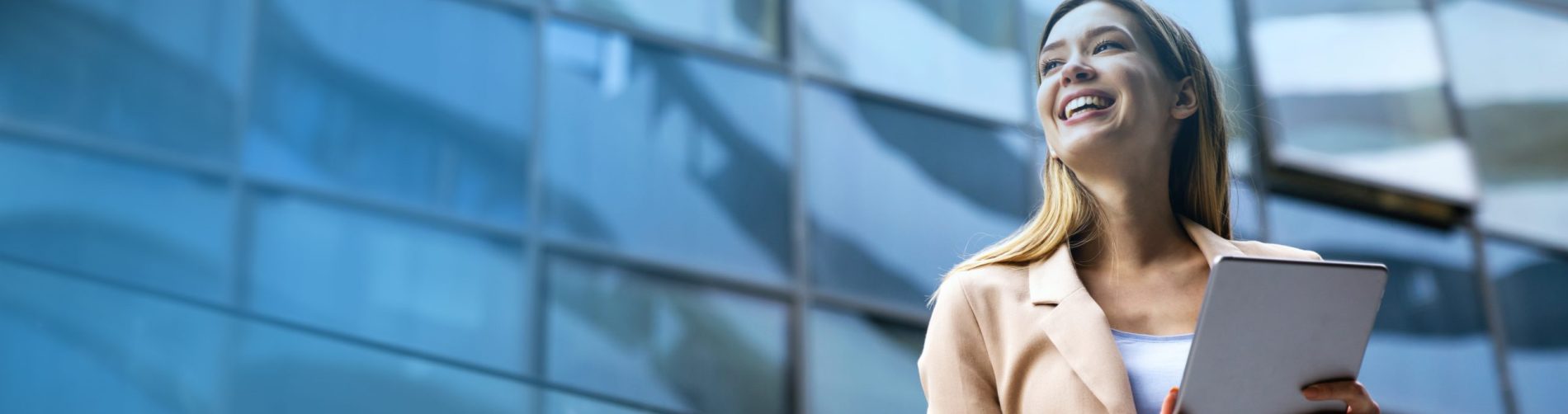 Portrait of a successful business woman using digital tablet in front of modern business building